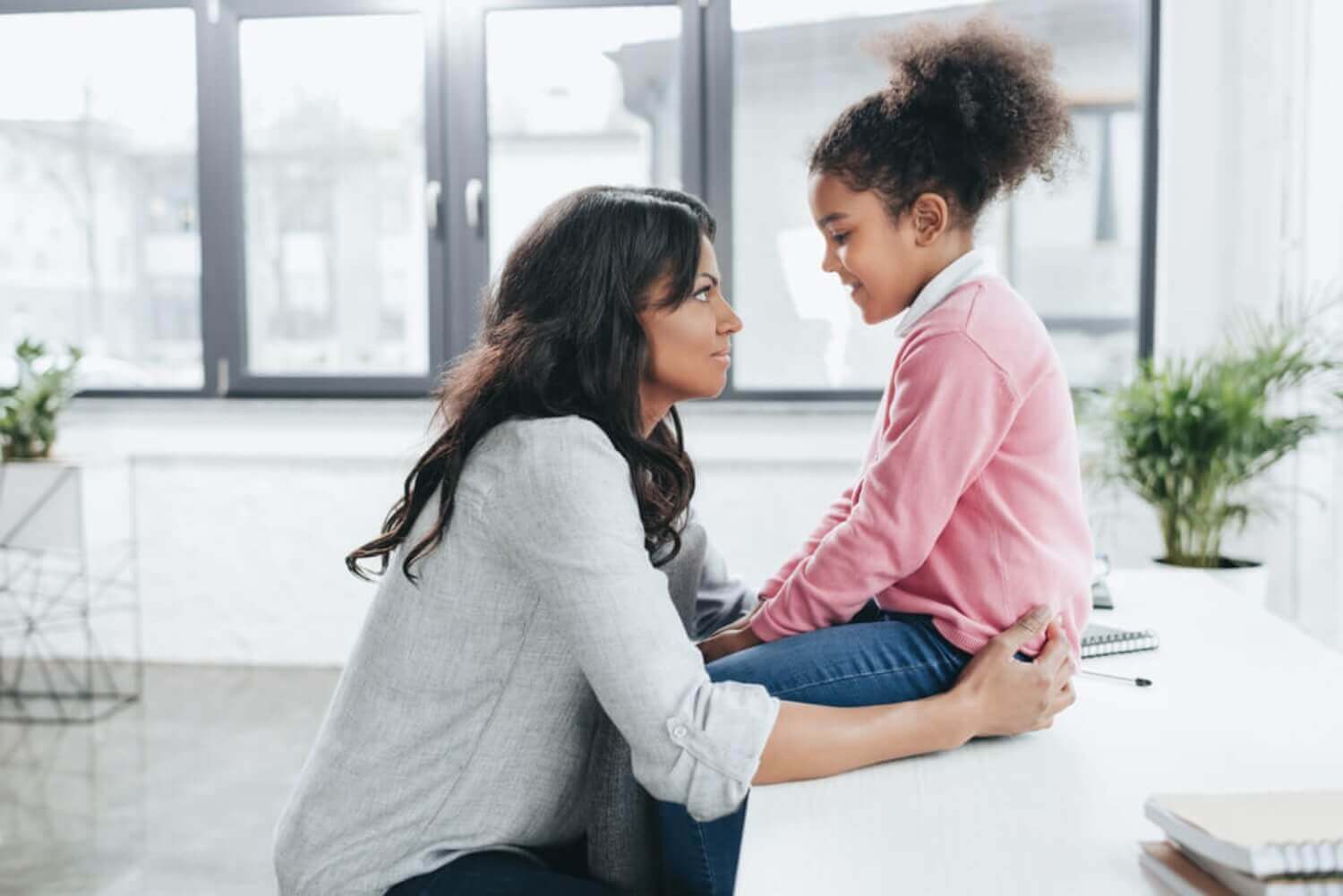 A mother looking into her daughter's eyes as they talk.
