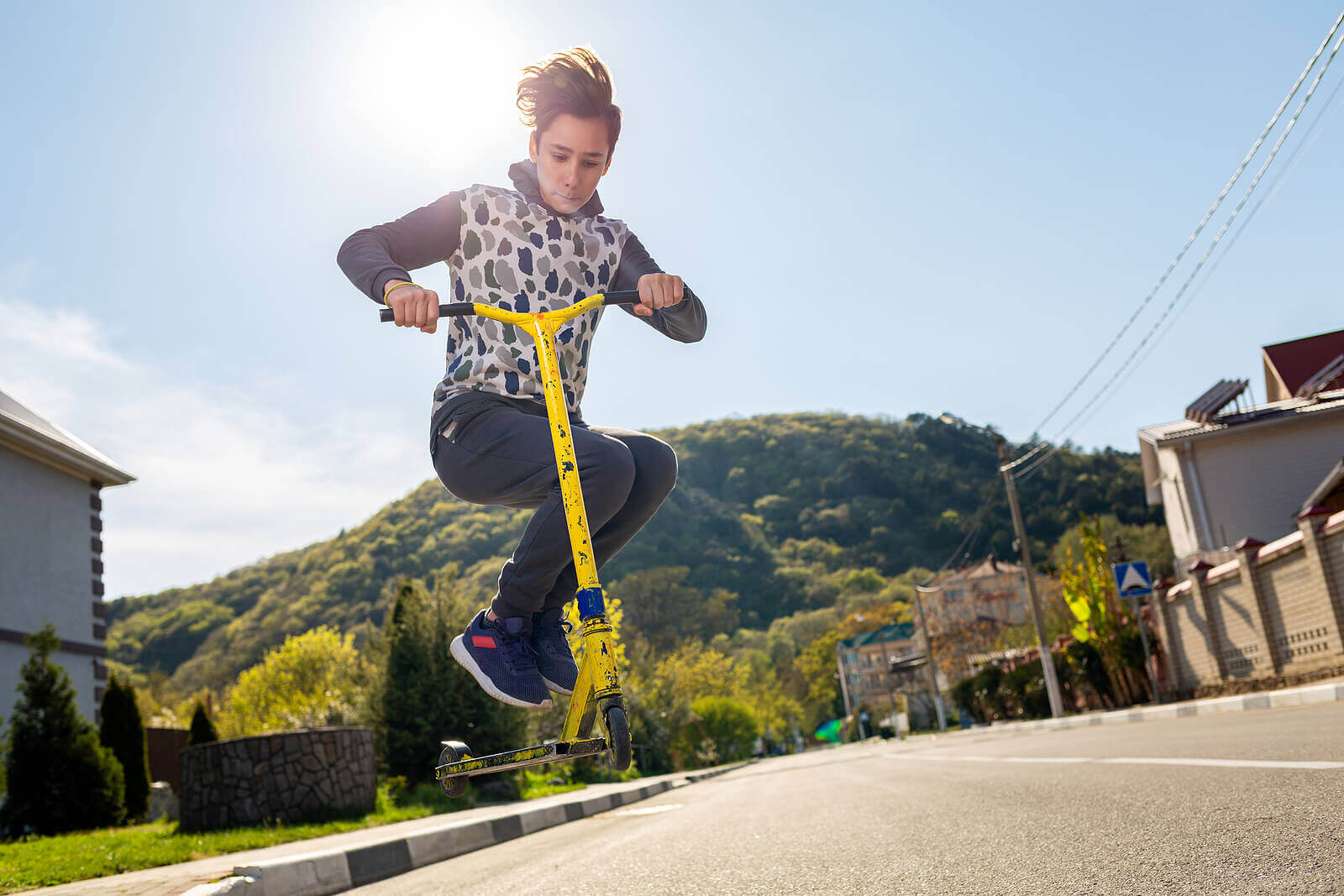 A teenager riding on a scooter.