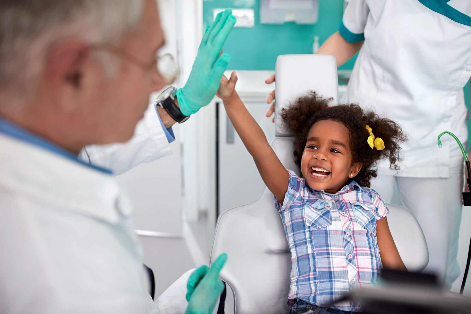 A young girl giving a high five to her dentist. 