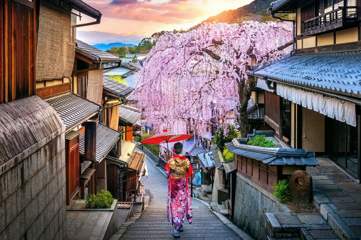 A woman walking down a narrow street in Japan.