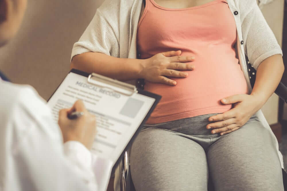 En lege som snakker med en gravid kvinne om hennes medisinske historie.