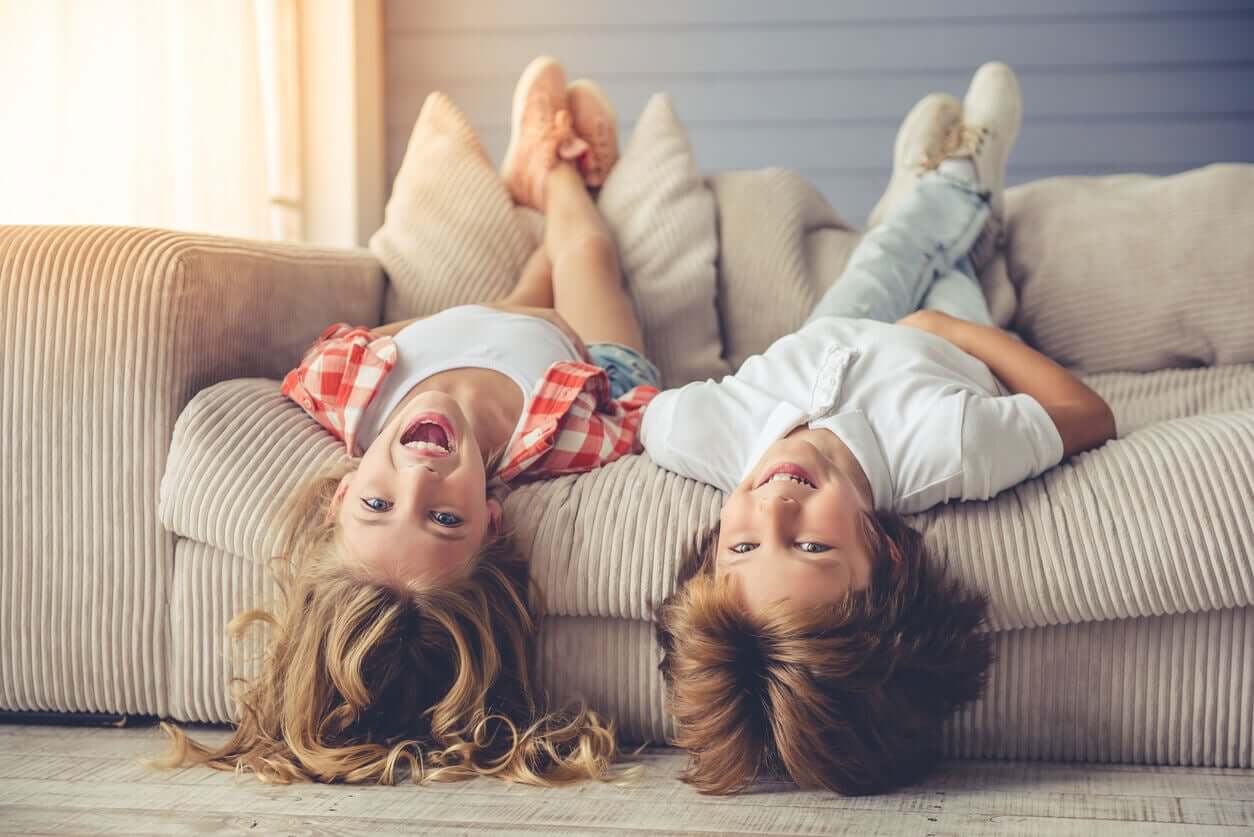 Children lying backward on a couch, laughing.