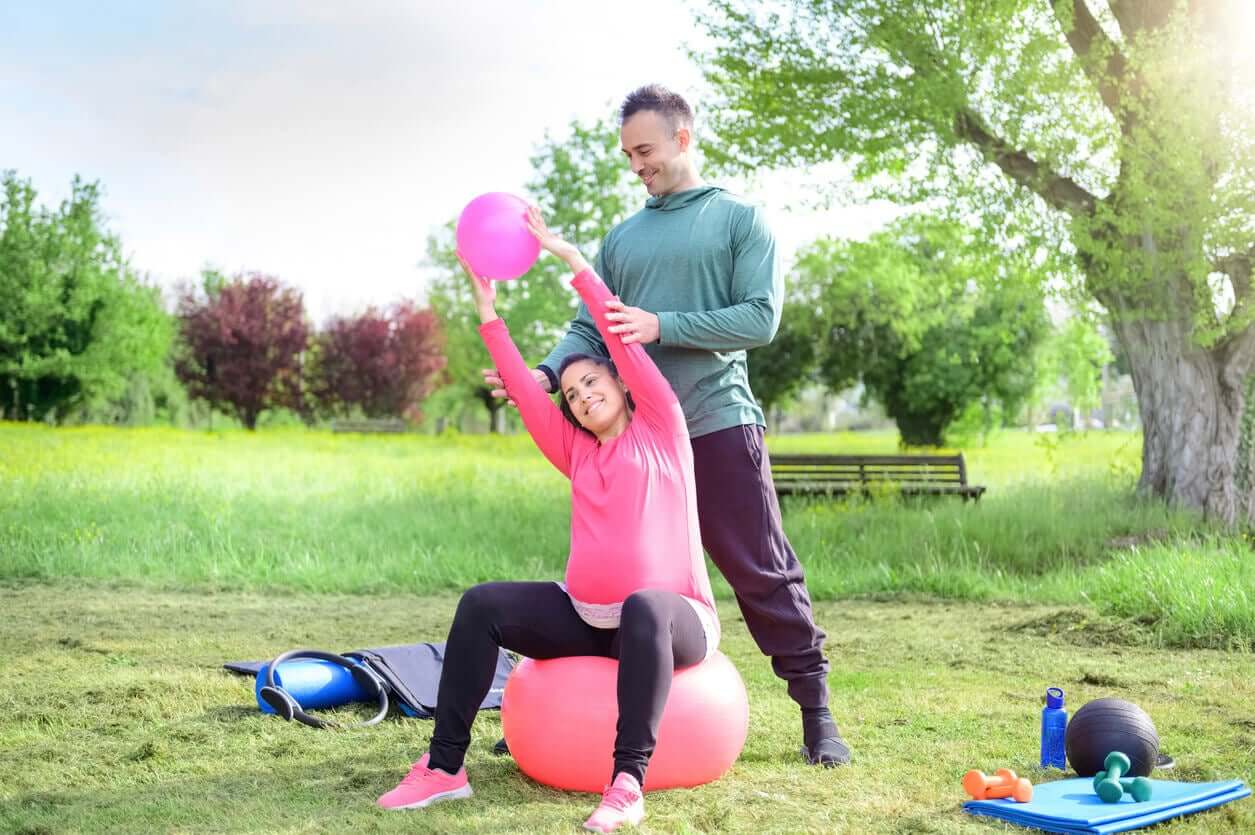 A pregnant women exercising in a park.
