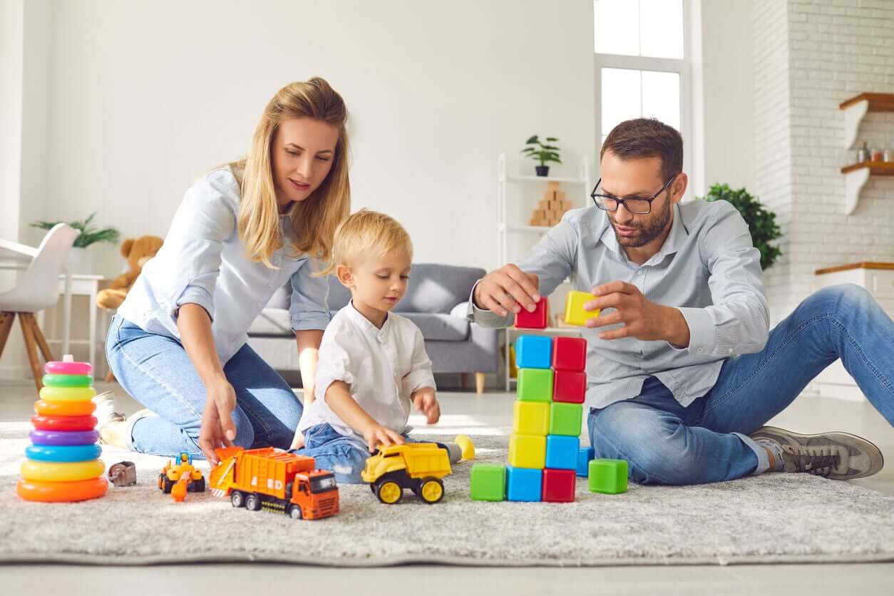 Foreldre leker med leker med babyen på gulvet.