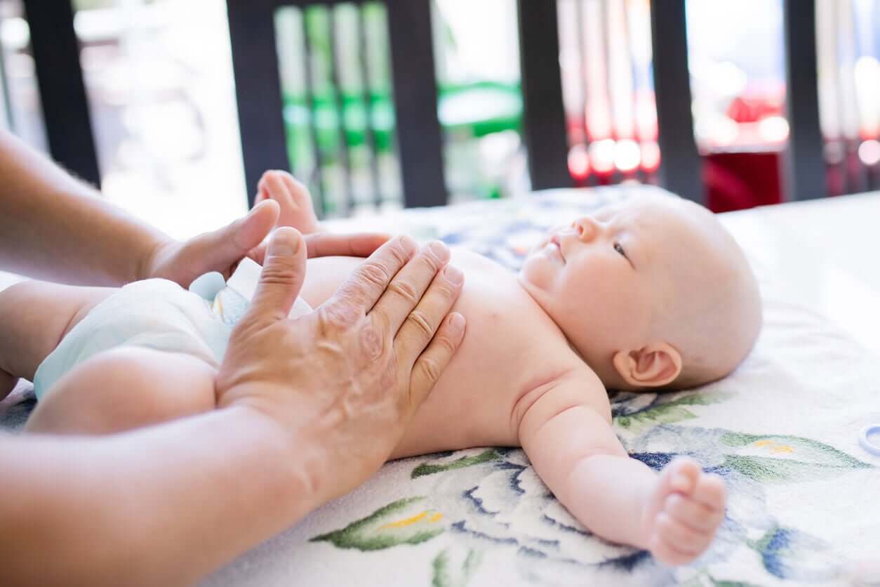 A parent performing massage on a baby's abdomen.
