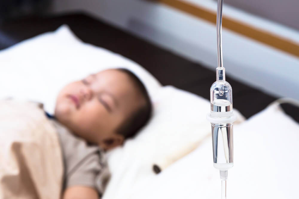 A baby in a hospital bed connected to an IV.