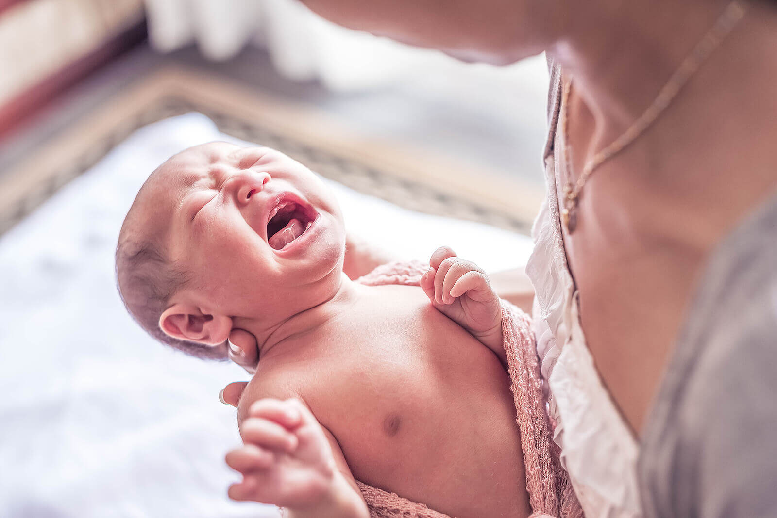 A mother looking down at her baby who won't stop crying.