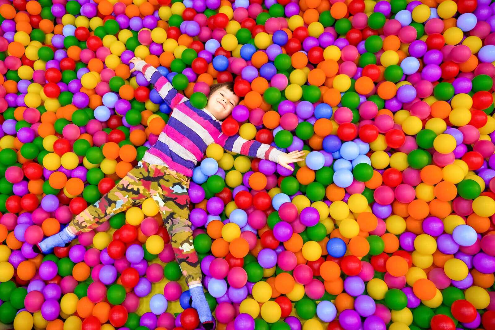 A child lying in a large ball pit.