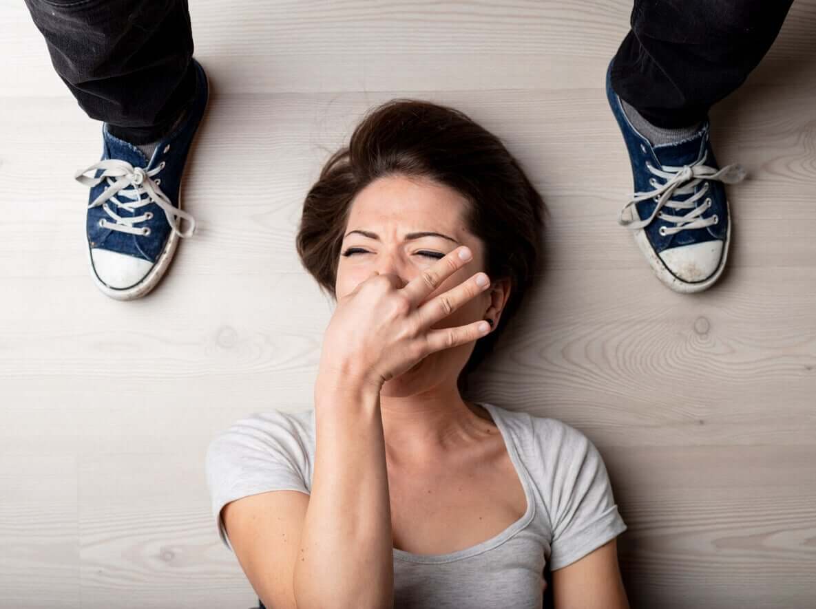 A woman plugging her nose because her teenage son's feet smell.