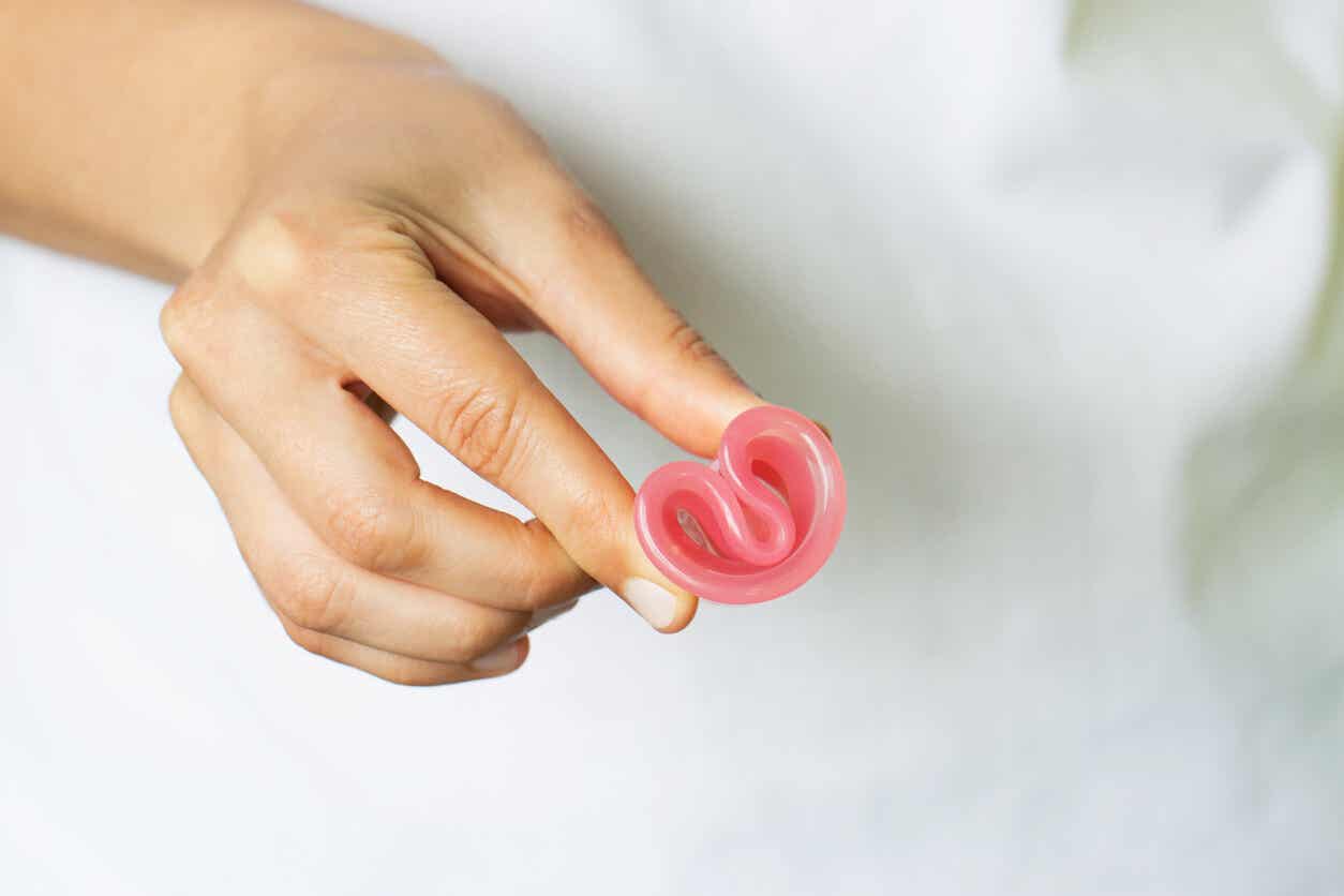 A woman holding a folded menstrual cup between her fingers.
