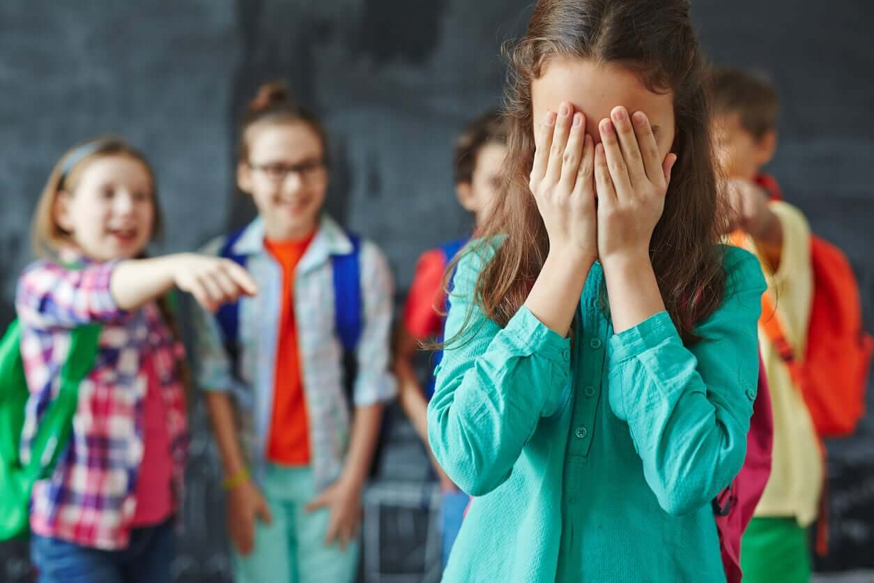 Studenter ler og peker på klassekameraten som dekker ansiktet hennes med hendene.
