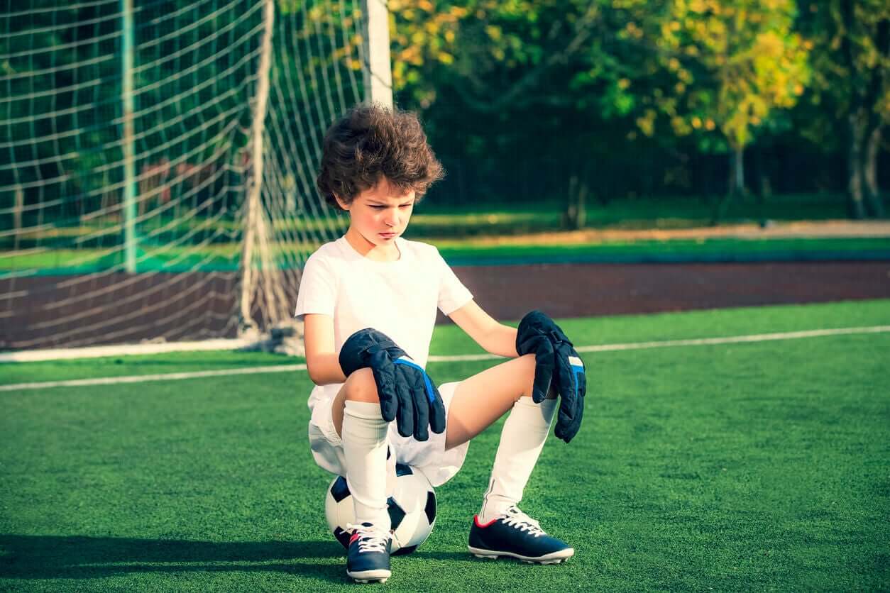 A child sitting on a soccer field, looking frustrated.