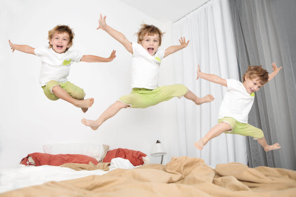 A toddler jumping on his bed.