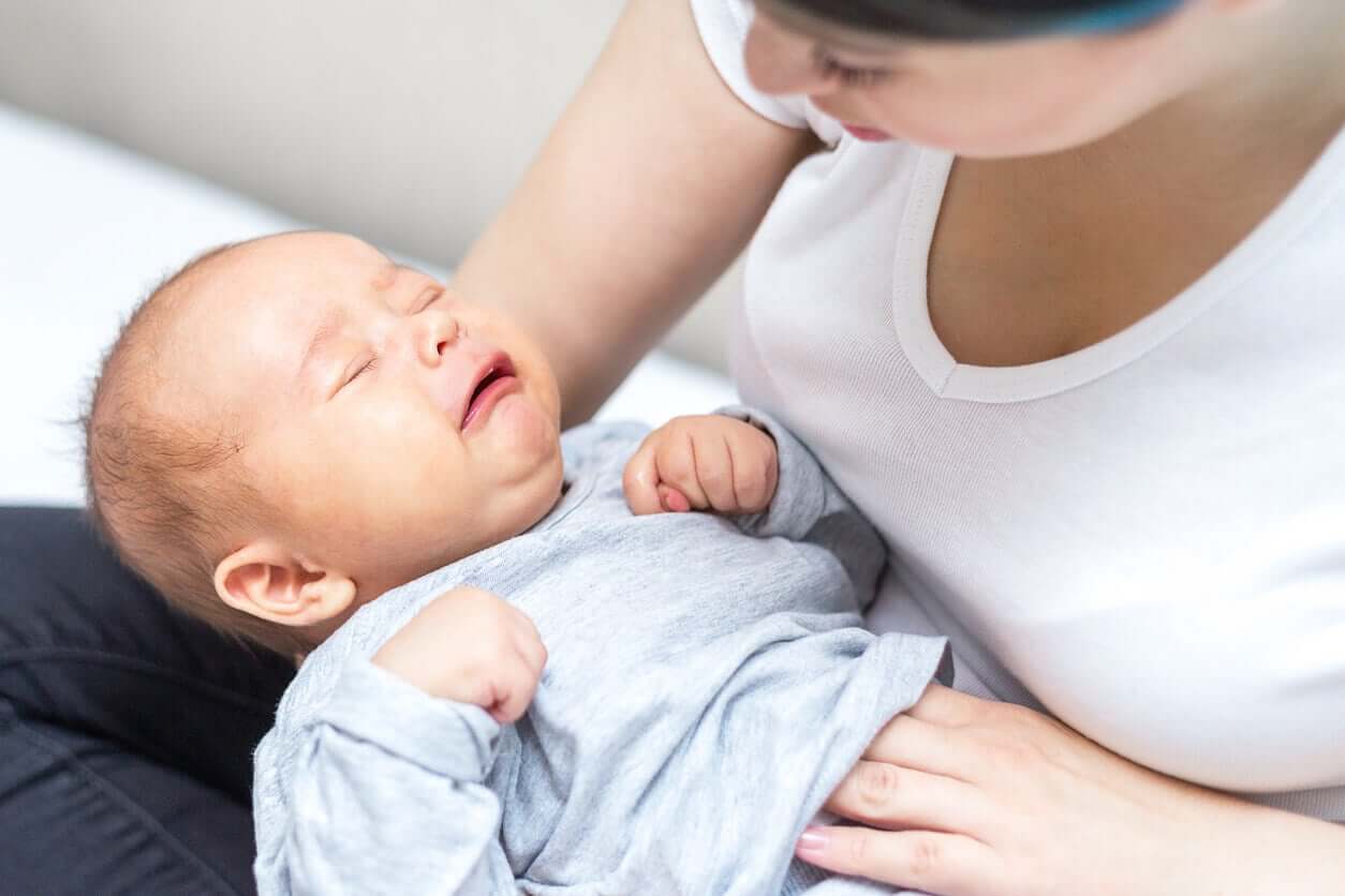 En mamma masserar sin gråtande babys mage.