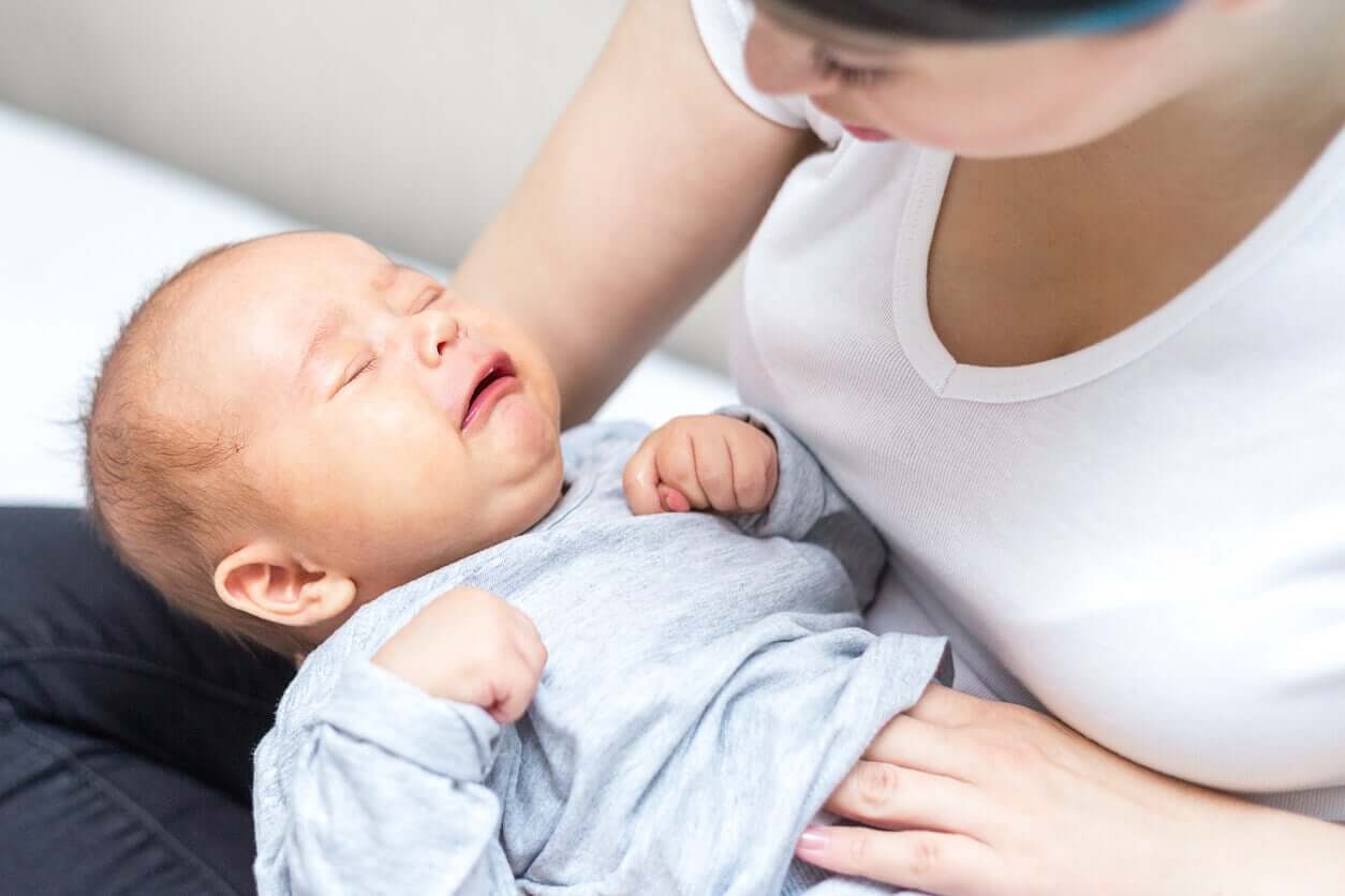 A mother massaging her crying baby's belly.