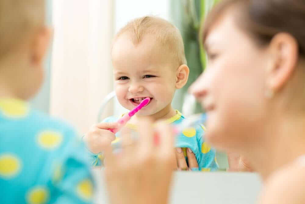 A mother helping her baby to brush his teeth.