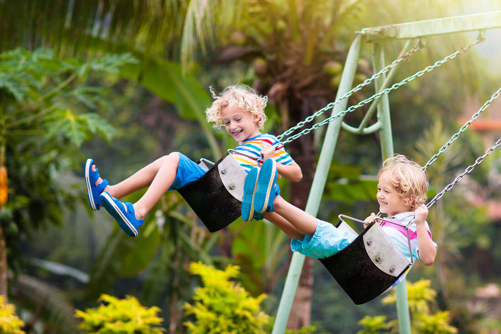 Two brothers swinging on a swingset.