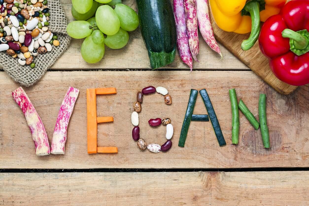 The word "vegan" written with vegetables.