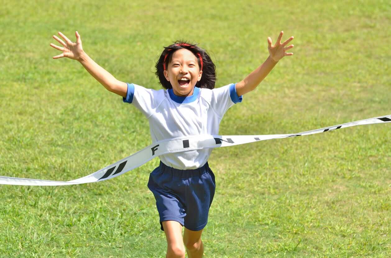 A young Asian girl winning a race.