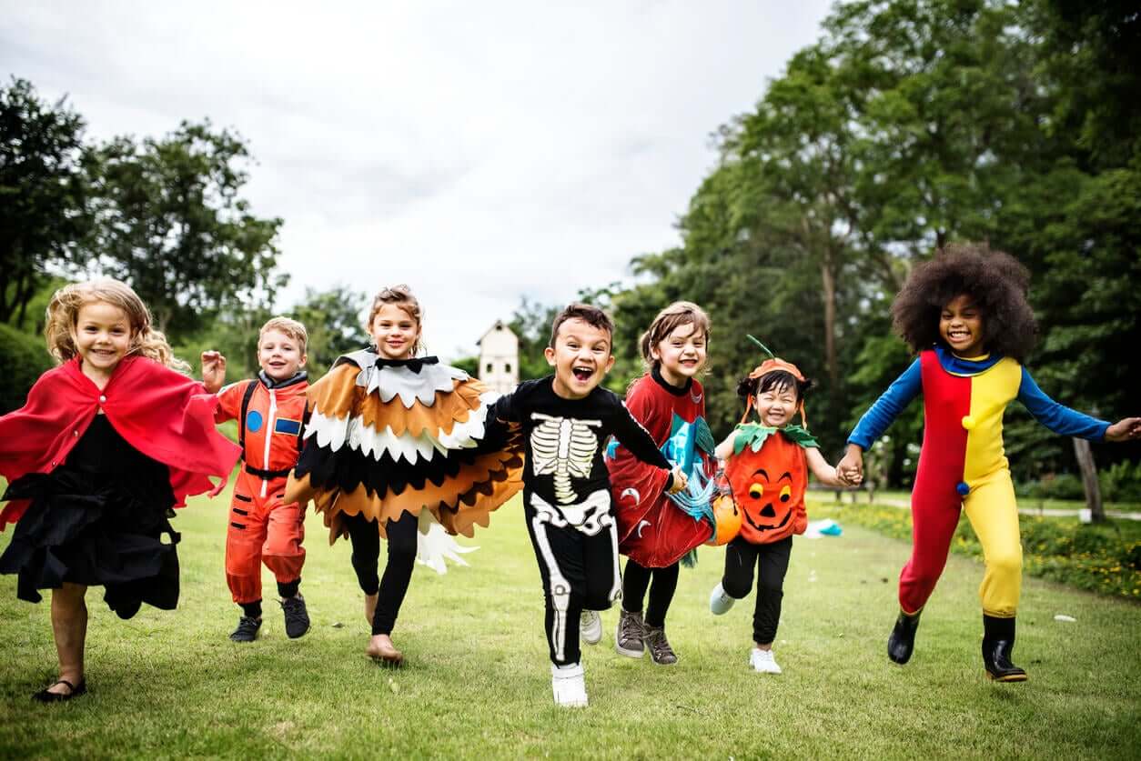 A group of children wearing costumes and running in the grass.