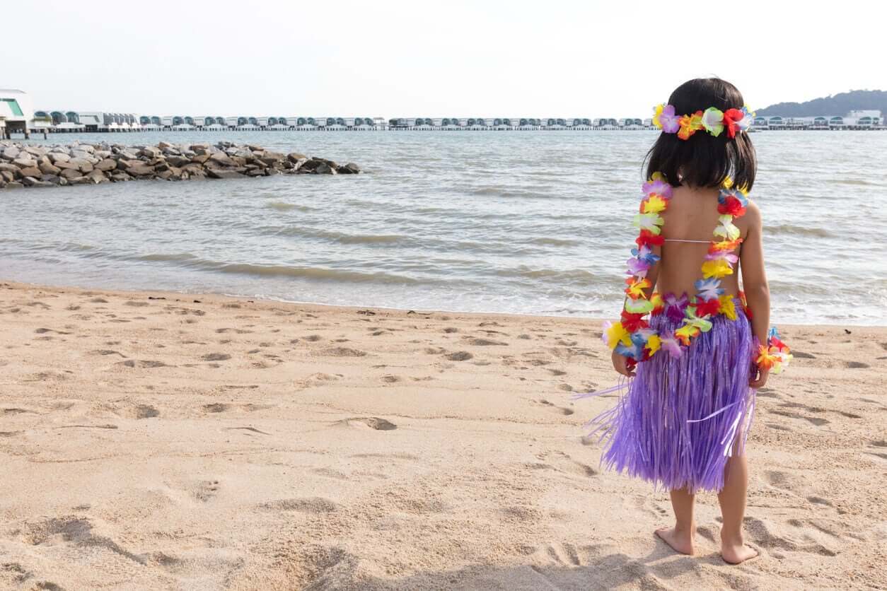 A little Hawaiian girl standing on the beach.