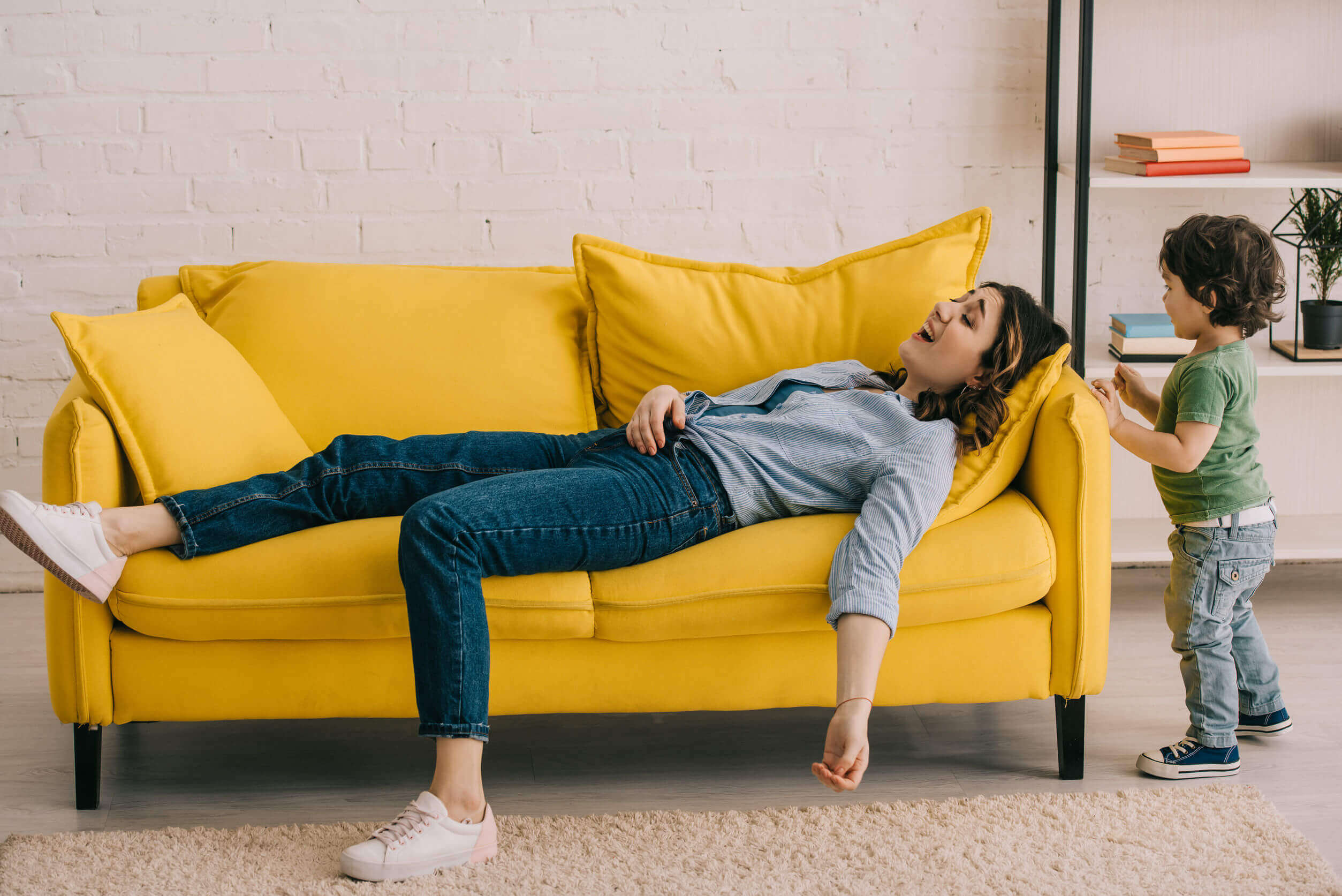 A mother lying on the couch looking overwhelmed.