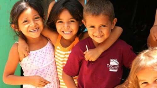 Three young children with their arms around one another.