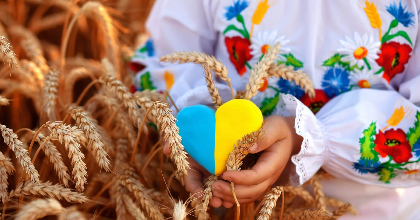 A Ukrainian girl wearing traditional dress and holding a small blue and yellow heart.