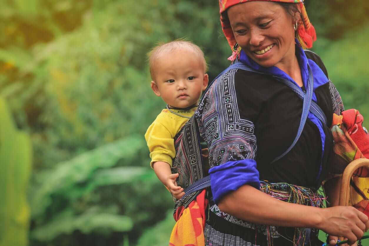 Vietnamilainen äiti kantaa lasta selässään.