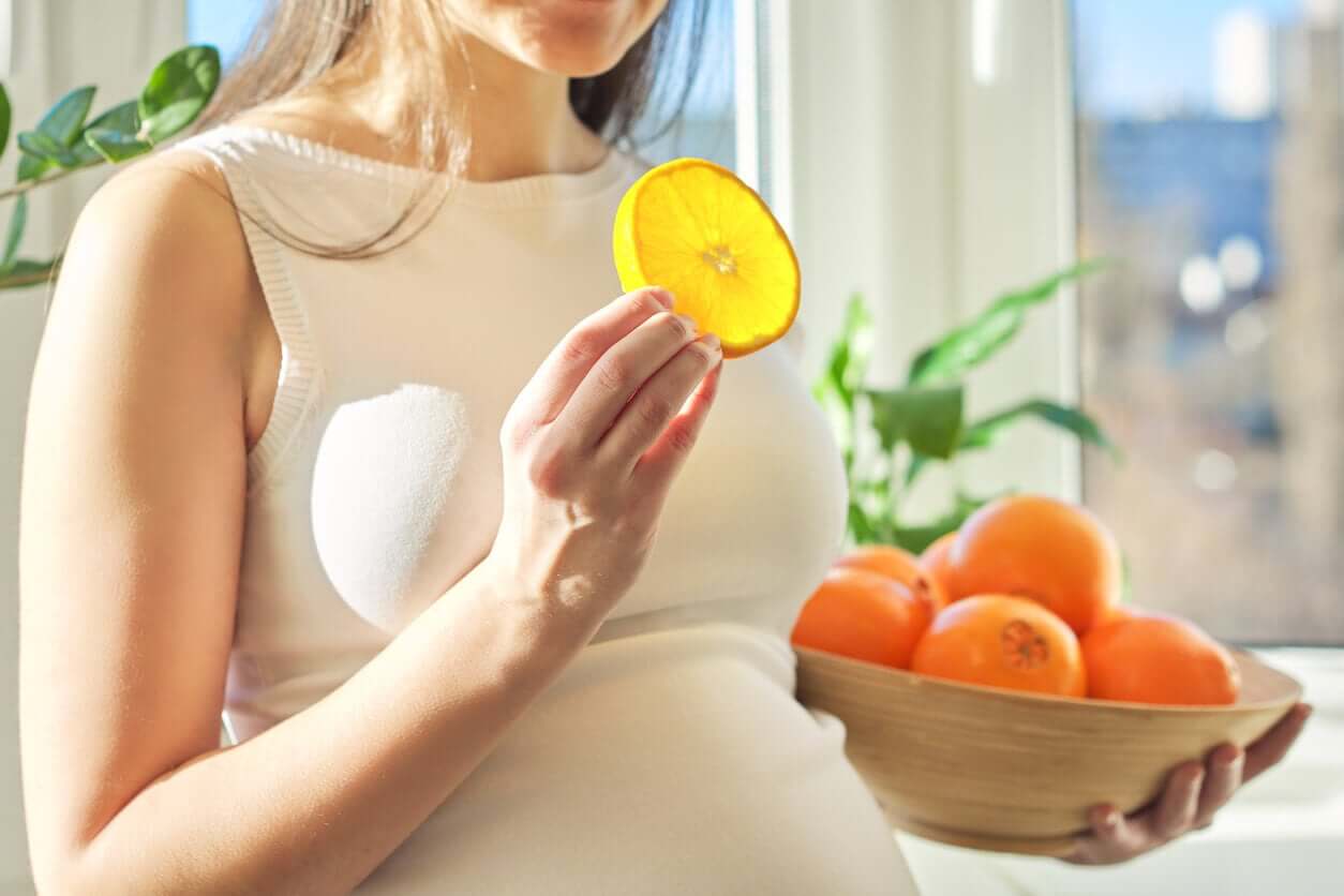 En gravid kvinne som spiser sitrusfrukter.