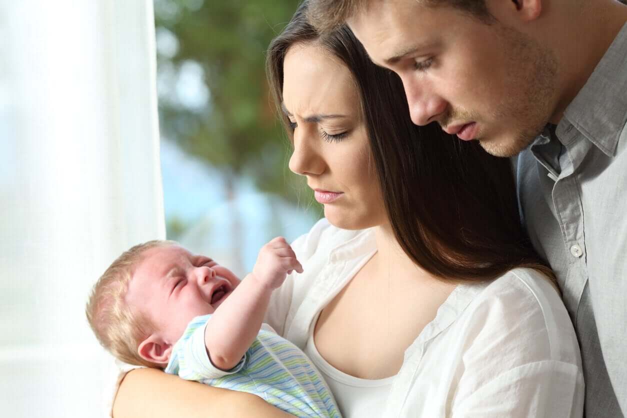 Parents looking overwhelmed as their baby cries.