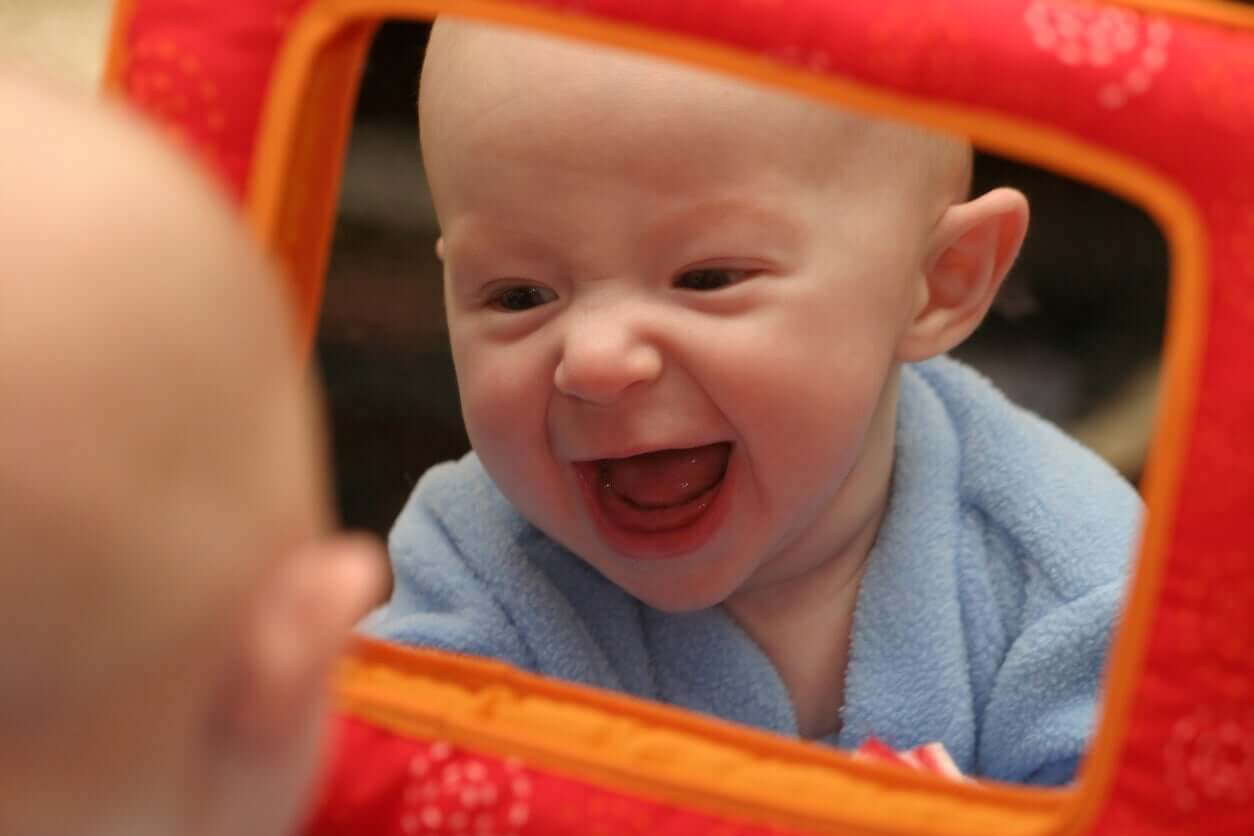 A baby laughing at his reflection in a toy mirror.