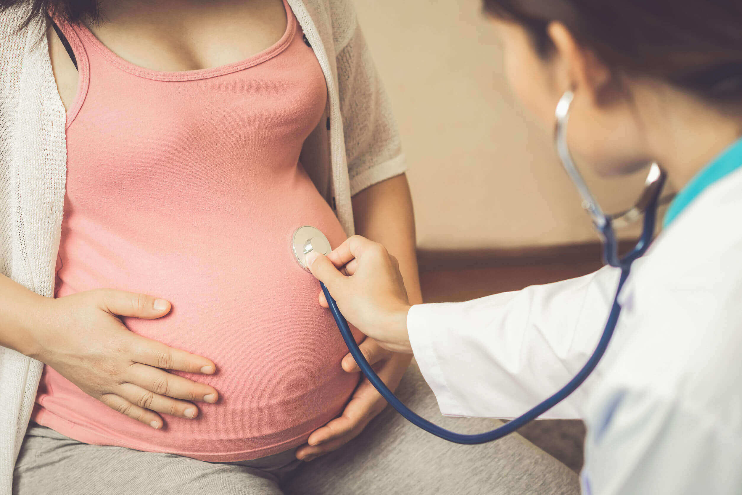 A doctor listening to a pregnant woman's belly with a stethescope.