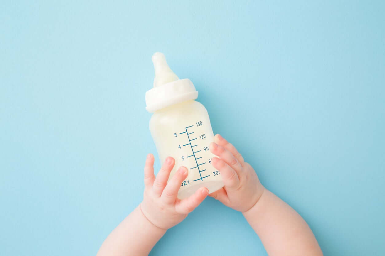 A baby holding a bottle.