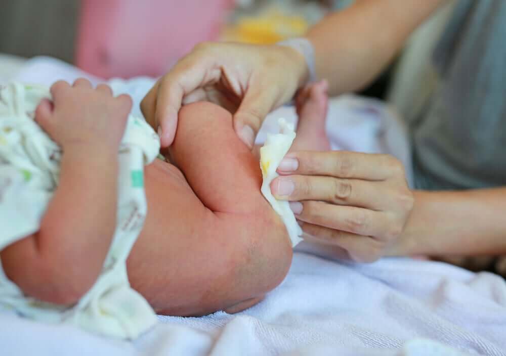 A mother cleaning a newborn baby's bottom.
