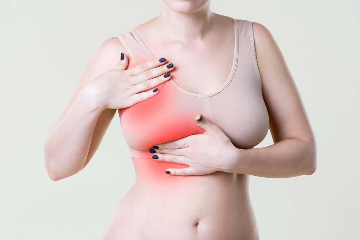 A woman pressing on one of her breasts with both hands.