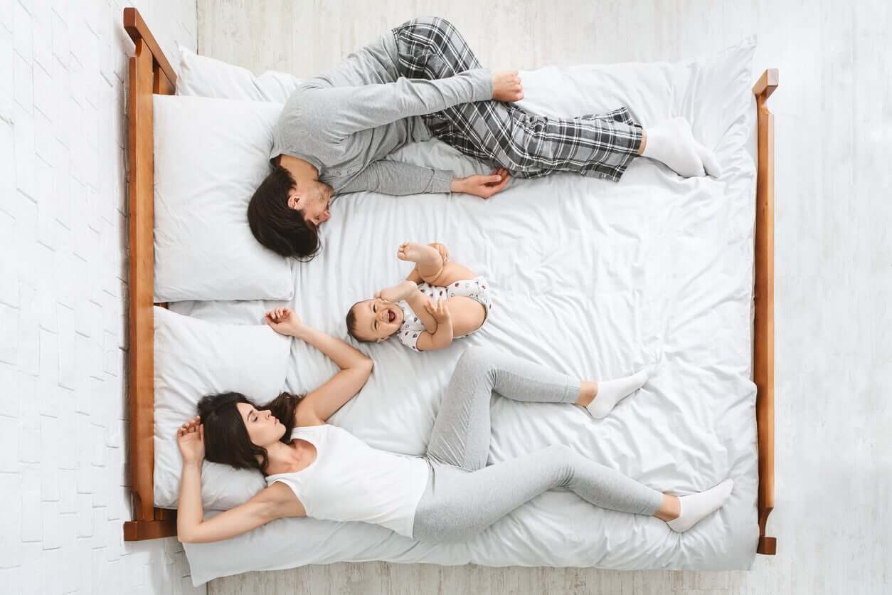 Forældre sover med vågen baby i midten