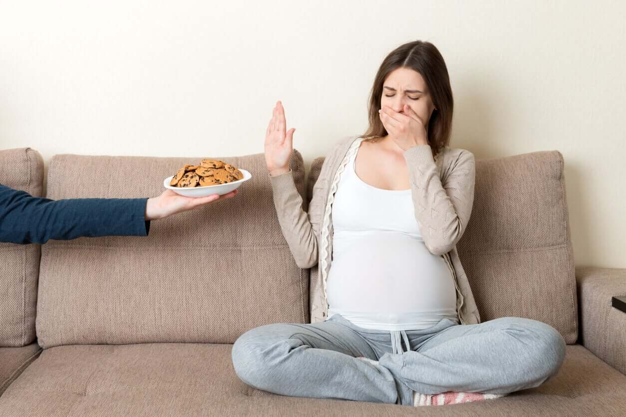 En gravid kvinna vägrar ta emot en tallrik med kakor.