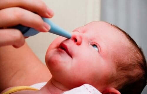 A woman using a rubber nasal aspirator on a newborn.