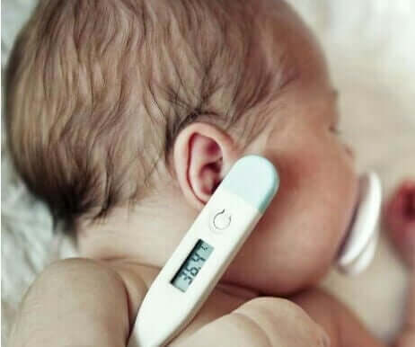 En nyfødt baby med et digitalt termometer under armen.