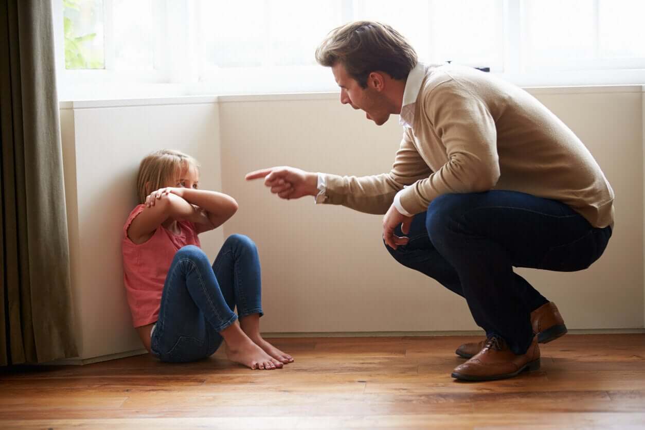 En far som truer datteren sin, som kryper sammen på gulvet.