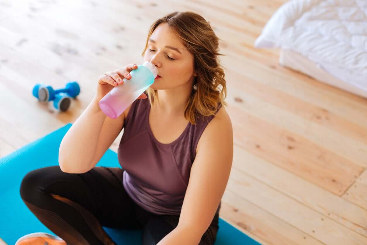 En kvinna som tar en paus från träningen för att dricka vatten.