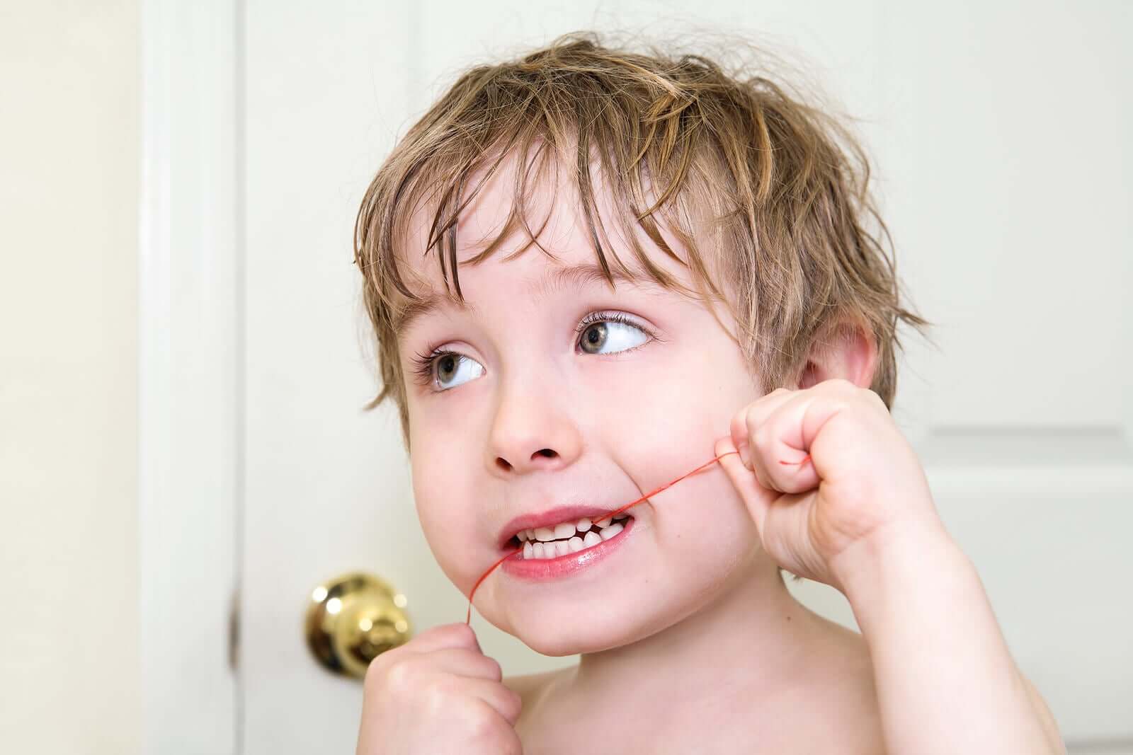 A little boy flossing his teeth.