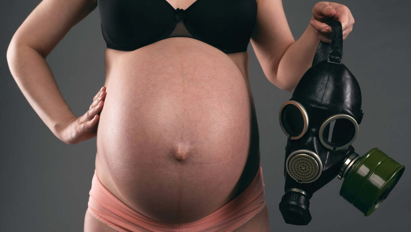 A pregnant woman holding a gas mask.