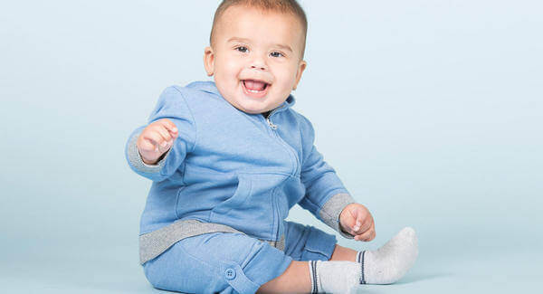 A baby boy sitting up and smiling.