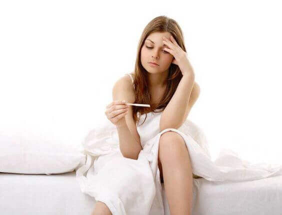 A woman looking sadly at a pregnancy test.