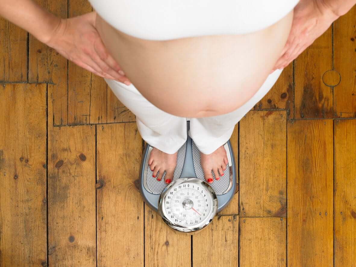 A pregnant woman standing on a scale.