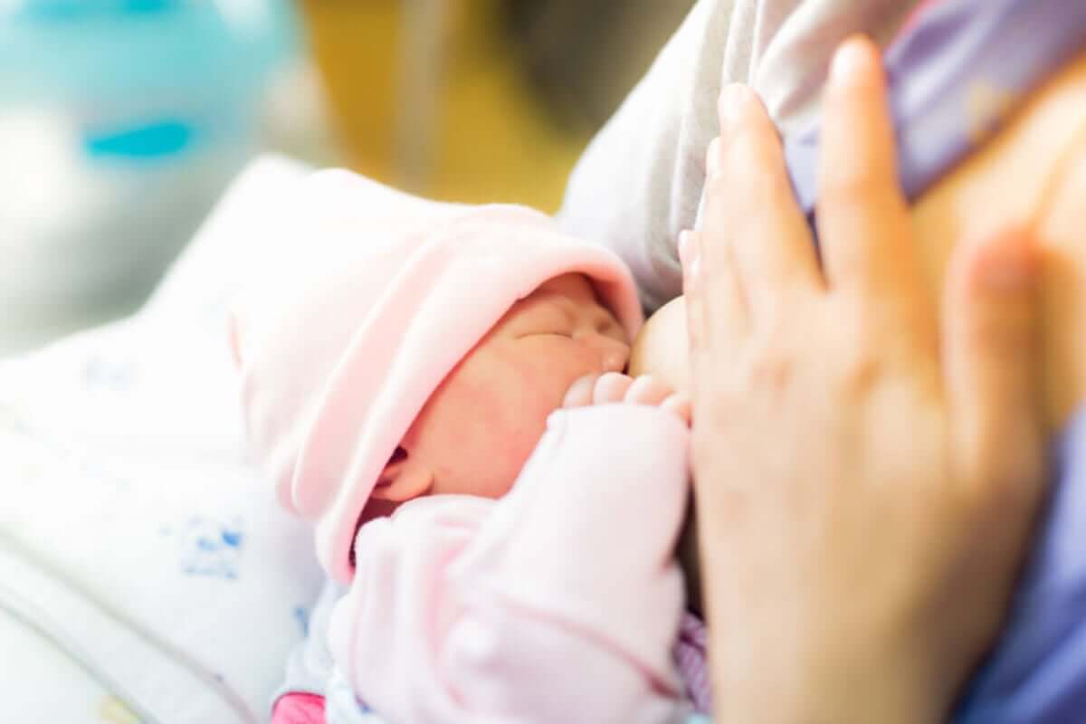 A tiny newborn girl breastfeeding.