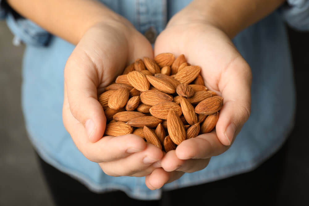 A person holding a handful of almonds.