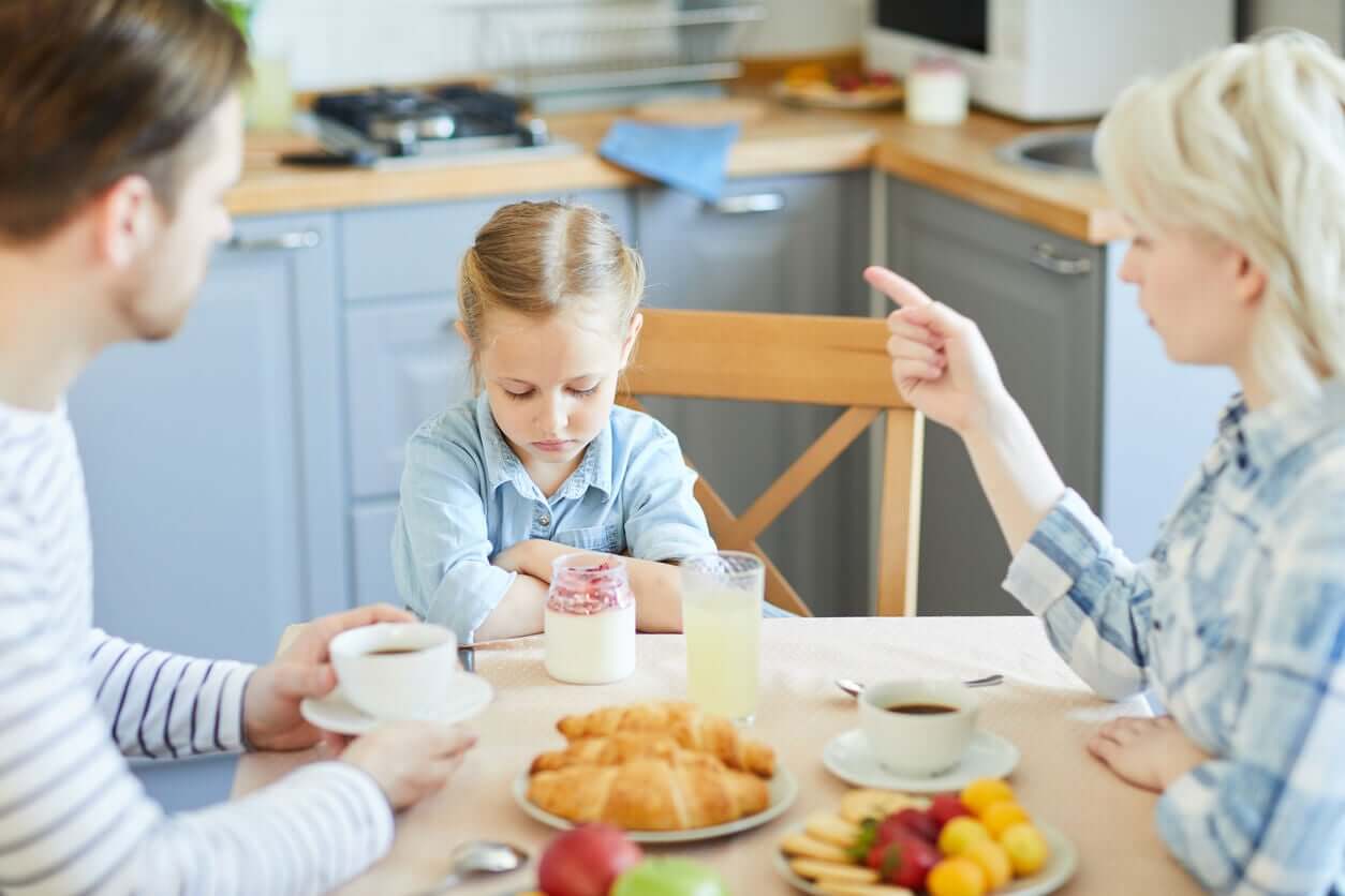 Parents scolding their daughter because she won't eat.